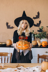 Mother and daughter making funny faces while holding a carved pumpkin for Halloween