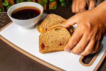 horizontal photo of traditional whole wheat artisan sliced bread with guava jam next to a cup of...