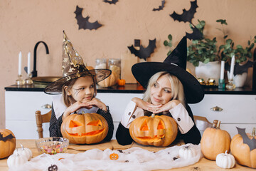 Mother and daughter wearing witch hats looking at carved pumpkins for Halloween party