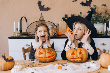 Mother and daughter wearing witch costumes making surprised faces for Halloween