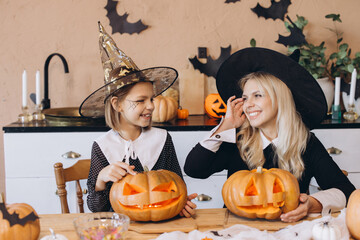 Mother and daughter carving pumpkins for Halloween party