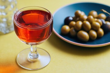 Enjoying a refreshing glass of vermouth rojo with marinated olives on a vibrant summer afternoon