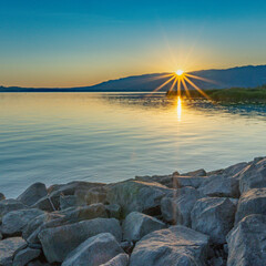 Sun on the shore of Lake Constance near Bregenz during sunrise, the sun comes over the mountain and...