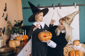 Mother and daughter wearing witch costumes preparing carved pumpkins for Halloween