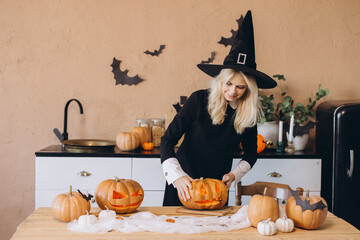 Woman carving pumpkins for Halloween party in kitchen