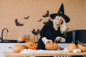 Young woman carving pumpkins for Halloween party celebration