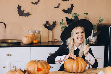 Young Woman Carving Pumpkins for Halloween Party in Kitchen