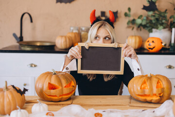 Woman celebrating Halloween hiding her face with a small blackboard