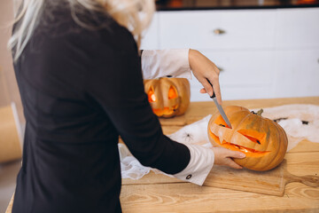 Woman carving a pumpkin for Halloween party at home