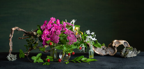 A floral arrangement with pale pink spirea, cinquefoil, and fragrant honeysuckle accented with driftwood. A romantic, organic arrangement.