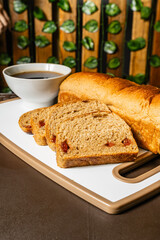vertical photo of traditional whole wheat artisan sliced bread with guava jam next to a cup of...