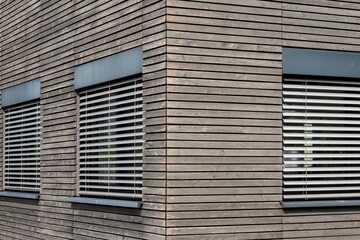 Modern wooden facade with venetian blinds creating geometric patterns