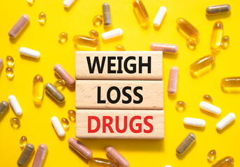 Medicine symbol. Concept words Weight Loss Drugs on wooden blocks. Beautiful yellow background with...