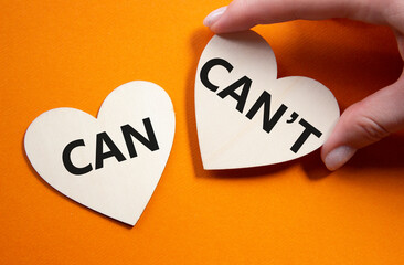 Can or Cant symbol. Concept word Can or Cant on wooden hearts. Businessman hand. Beautiful orange...