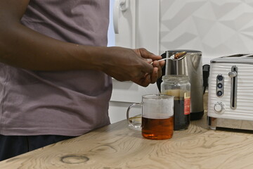 Detail of African man's hands preparing tea. Adding honey