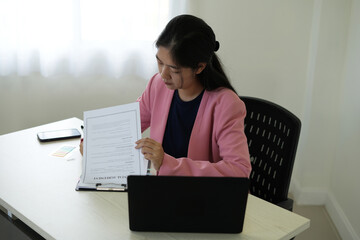 Real estate gent asian woman is reading and checking paper documents, signing the contract to send...
