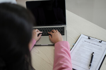Real estate gent asian woman is reading and checking paper documents, signing the contract to send...