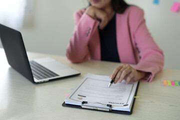 A young asian female Head of HR is reading resume and making a call for the recruitment interview...