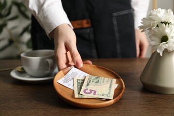 Waitress taking tips from wooden table in cafe, closeup