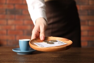 Waitress taking tips from wooden table in cafe, closeup
