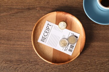 Tips, receipt and dirty cup on wooden table, flat lay