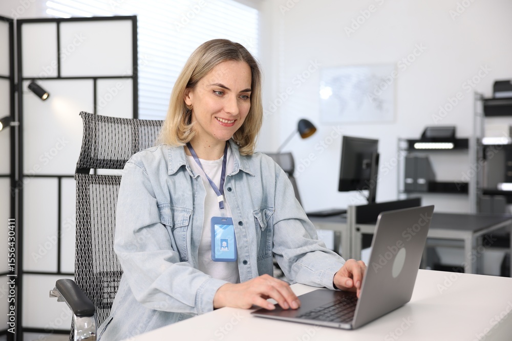 Poster smiling engineer working with laptop at table in office