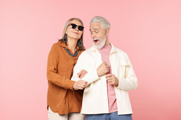 Senior couple in stylish outfits on pink background
