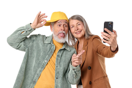 Senior couple in stylish outfits taking selfie on white background