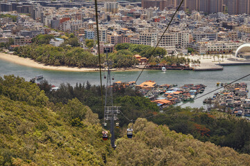 A cable car ascends a hill, with a vibrant city in the background
