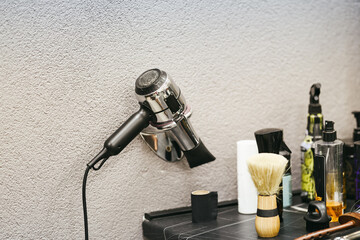 Hair dryer mounted on wall in modern barbershop, surrounded by grooming tools and spray bottles,...