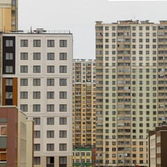 High-rise residential buildings with varied facades stand closely together in a modern urban...