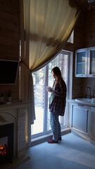 Young woman enjoying morning coffee in her home, looking out the window