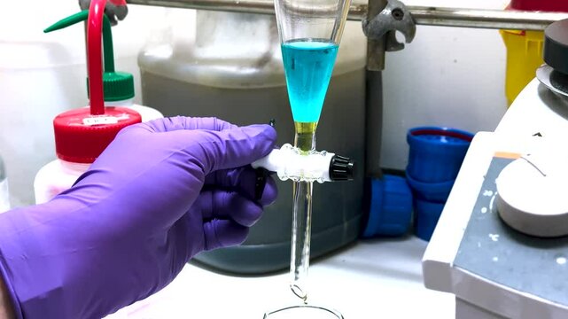 Separation of organic layer and water layer in separating funnel in a chemistry lab for education purpose. Effervescent of carbon dioxide bubble in organic layer. 4K scientific background concept.