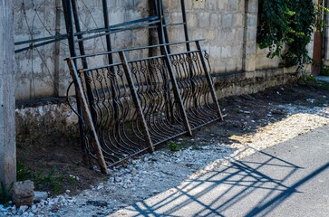 A fence is leaning against a wall. The fence is made of metal and has a lot of detail