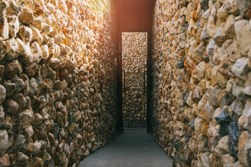 Serene Pathway Between Stone Walls Leading to Bright Light in a Narrow Alleyway