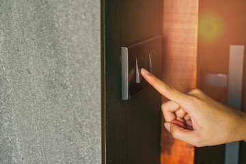 Hand Press switch. Finger Touching Modern Light Switch on Stylish Wall with Warm Illumination in Contemporary Interior Design Setting