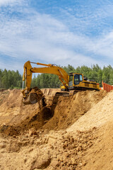 Obraz premium A caterpillar tractor works with a bucket in a sand pit. Sand mining