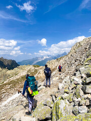 Backpacking Along a Rugged Alpine Trail in the High Mountains. 3 hikers on TMB (Tour du Mont Blanc) trail. Vertical. 