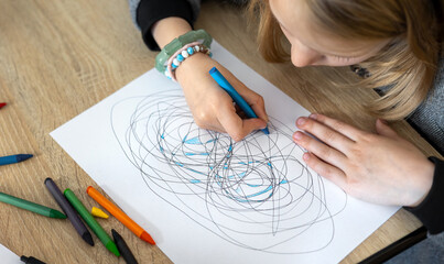 Child draws fractal patterns with crayons as part of art therapy. Creative activity for emotional...