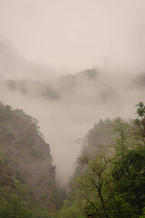 Foggy mountain landscape with lush greenery and dramatic cliffs