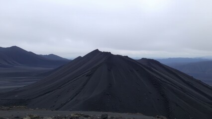 Dark Volcanic Mountain Against Pale Sky

