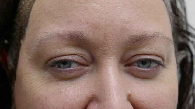 Extreme close-up: Beautician revealing microblading results, carefully guiding client in opening eyes after precise eyebrow tattoo treatment with professional skill and aesthetic enhancement