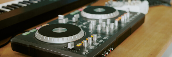Closeup showing DJ controller and electronic keyboard on wooden table, music production equipment...