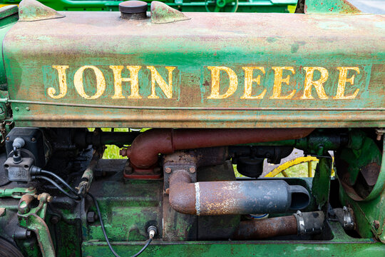 A weathered John Deere decal on a rusty tractor hood. 