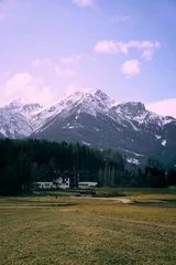 Fotobehang Picturesque alpine landscape showcasing snow-capped mountains and a tranquil farmhouse nestled in a grassy valley © Robin