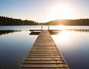 Obraz premium The sun-drenched surface of a calm, vast lake, with a single, small boat dock extending into the tranquil water.