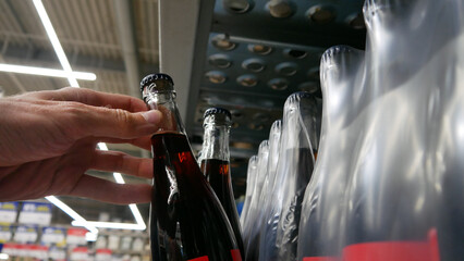 Close-up of a male customer hand taking a glass bottle of cola