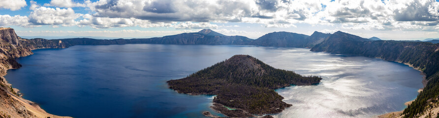 This is a panoramic view of Crater Lake National Park in Oregon, featuring the iconic Wizard Island at the west end. Crater Lake, formed in the caldera of a collapsed volcano, Mount Mazama.