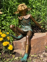 Bronze statue of Leprechaun in flower garden close up