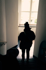 Mysterious figure descending stairs in an Alpine building during the daylight hours